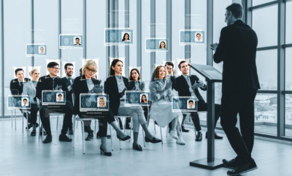 A Black woman in a blue shirt smiling while she types on her phone; a graphic of lines mapping the contours of her face is superimposed onto the image